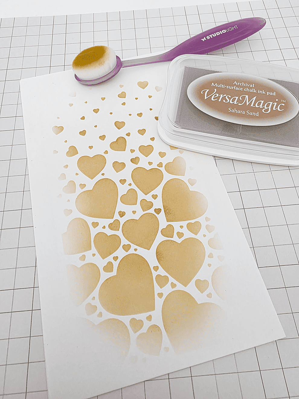 Stencil Schablone mit Herzmotiv, eingefärbt mit goldener Stempelfarbe und Applikator