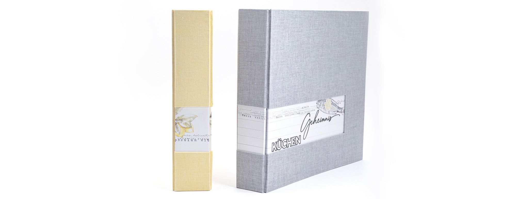 Gelber Schuber und grauer Ordner mit "KÜCHEN Geheimnis"-Etikett.