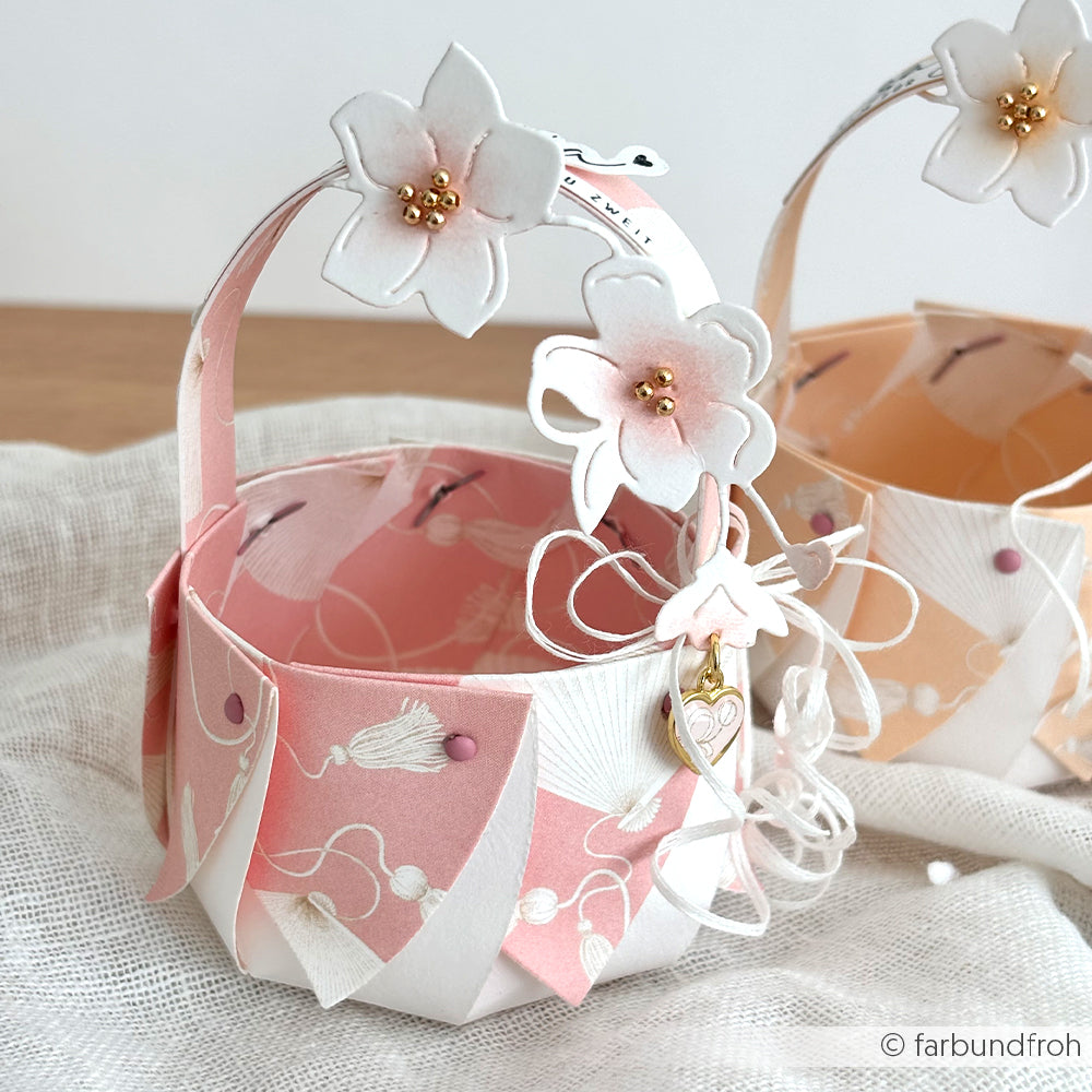 Handgemachter Papierkorb von Alexandra Renke, gefertigt aus Designpapier mit rosa und weißen Blumenmustern und Blumenakzenten am Henkel - ideal für Buchbinderei oder kreative Papierprojekte.
