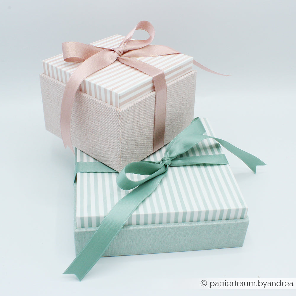 Zwei pastellfarbene Geschenkboxen mit gestreiften Deckeln und Schleifenband - eine rosa, eine mintgrüne - ineinander gestapelt: eine perfekte Alexandra Renke-Inspiration, wenn Sie mit PAPPKit eine Geschenkverpackung selbst machen oder eine Einsteckbox basteln wollen.