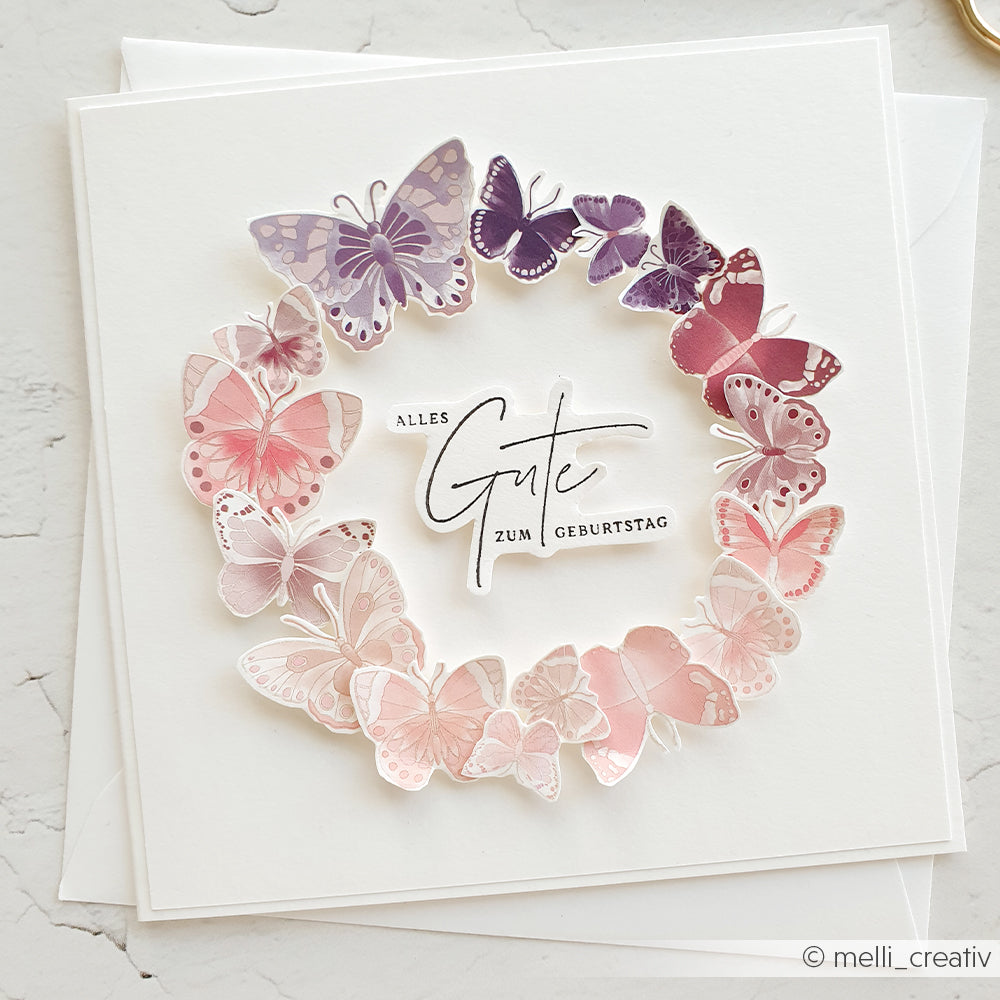 Quadratische Geburtstagskarte von Alexandra Renke mit einem Kranz aus rosafarbenen und lila Schmetterlingen und dem Text "Alles Gute zum Geburtstag" - ideal für Bastelprojekte Motive oder zum Hinzufügen von Details mit Transferfolien Basteln.