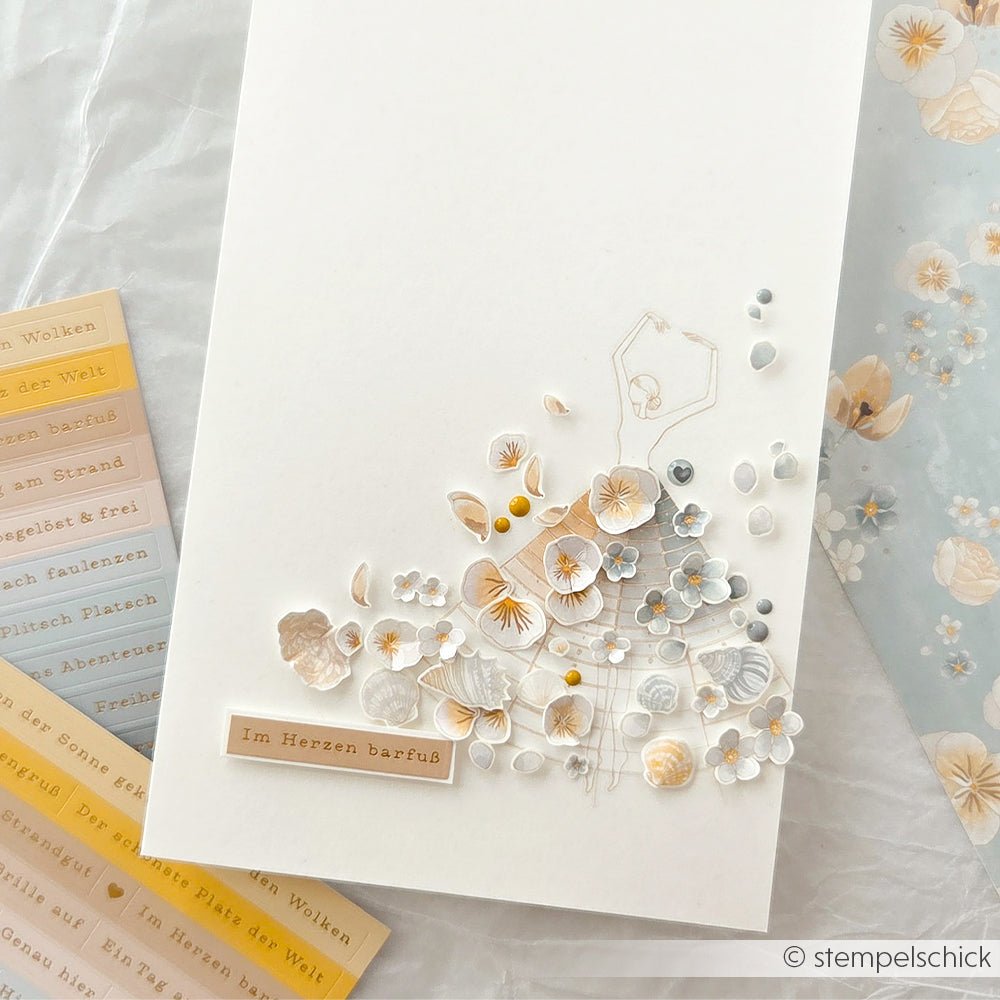 Eine handgefertigte Alexandra Renke Karte mit pastellfarbenen Blumen, goldenen Akzenten und der Aufschrift "Im Herzen barfuß". Perfekt zum Verzieren mit Rub-On Meeresbrise für einen Hauch von maritimer Eleganz.