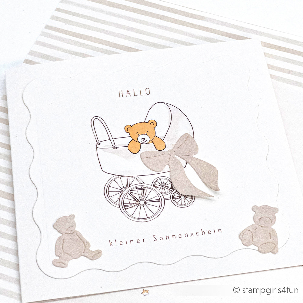 Quadratische Babykarte von Alexandra Renke, gestaltet mit Designpapieren, mit einem Teddybär im Kinderwagen, einer Schleife und zwei kleinen Bärenanhängern aus den Motivstanzen. Der Text lautet "Hallo kleiner Sonnenschein.