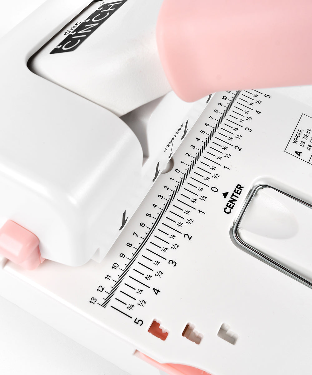 Nahaufnahme eines weißen und rosafarbenen Lochers mit Messmarkierungen und einer Papierführung.