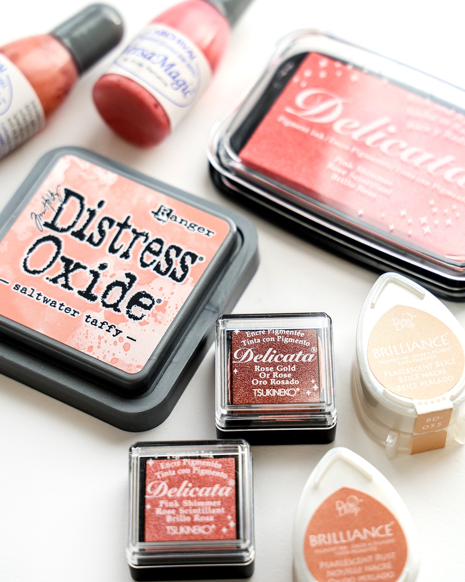 Verschiedene Stempelkissen und Flaschen zum Stempeln und Basteln, angeordnet auf einer weißen Fläche.