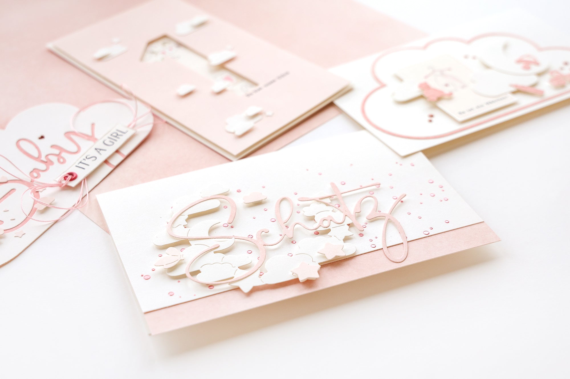 Drei rosa-weiße Grußkarten mit zarten Motiven und deutschem Text, angeordnet auf einer weißen Fläche.