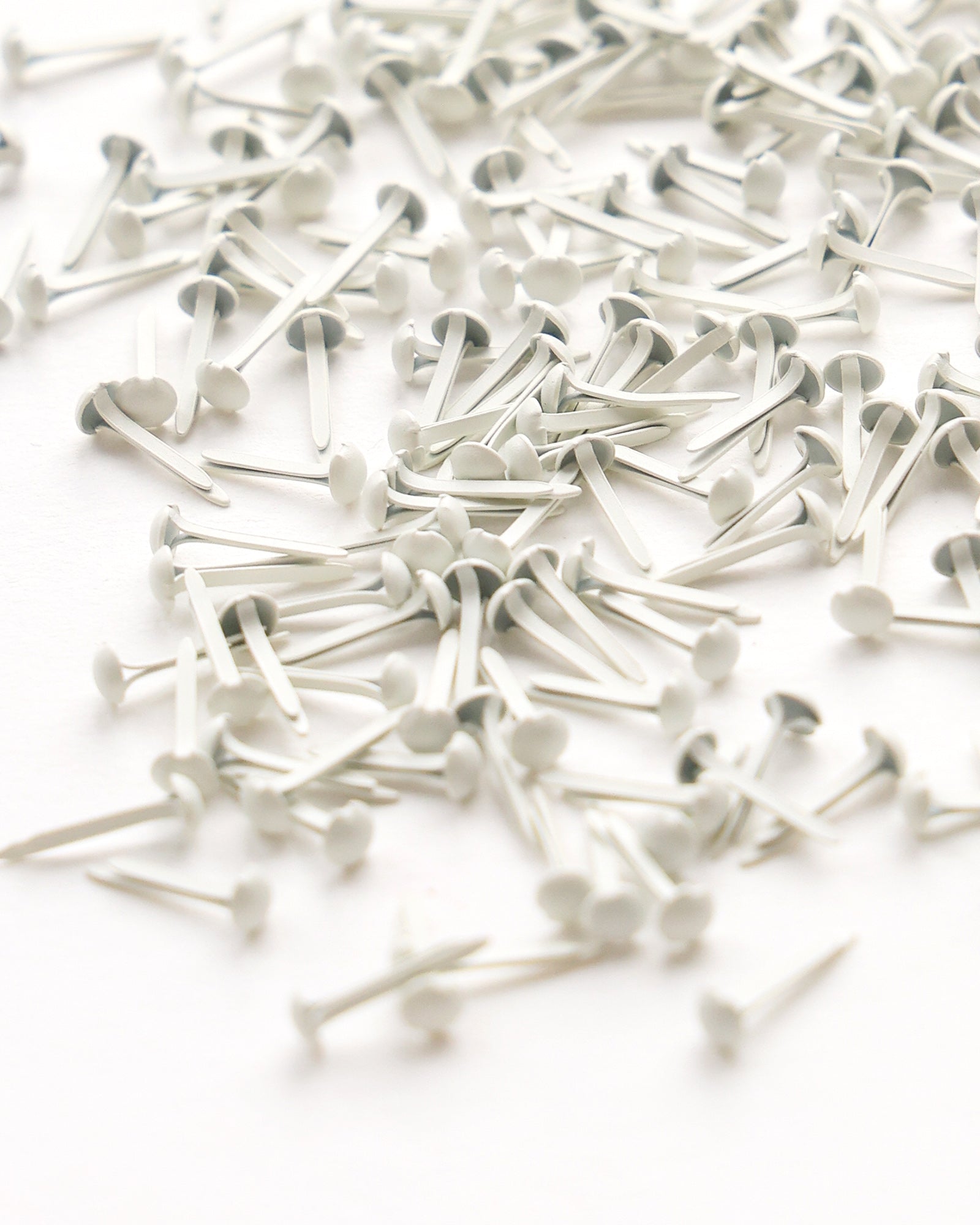 Ein verstreuter Stapel weißer Papierverschlüsse auf einer weißen Fläche.