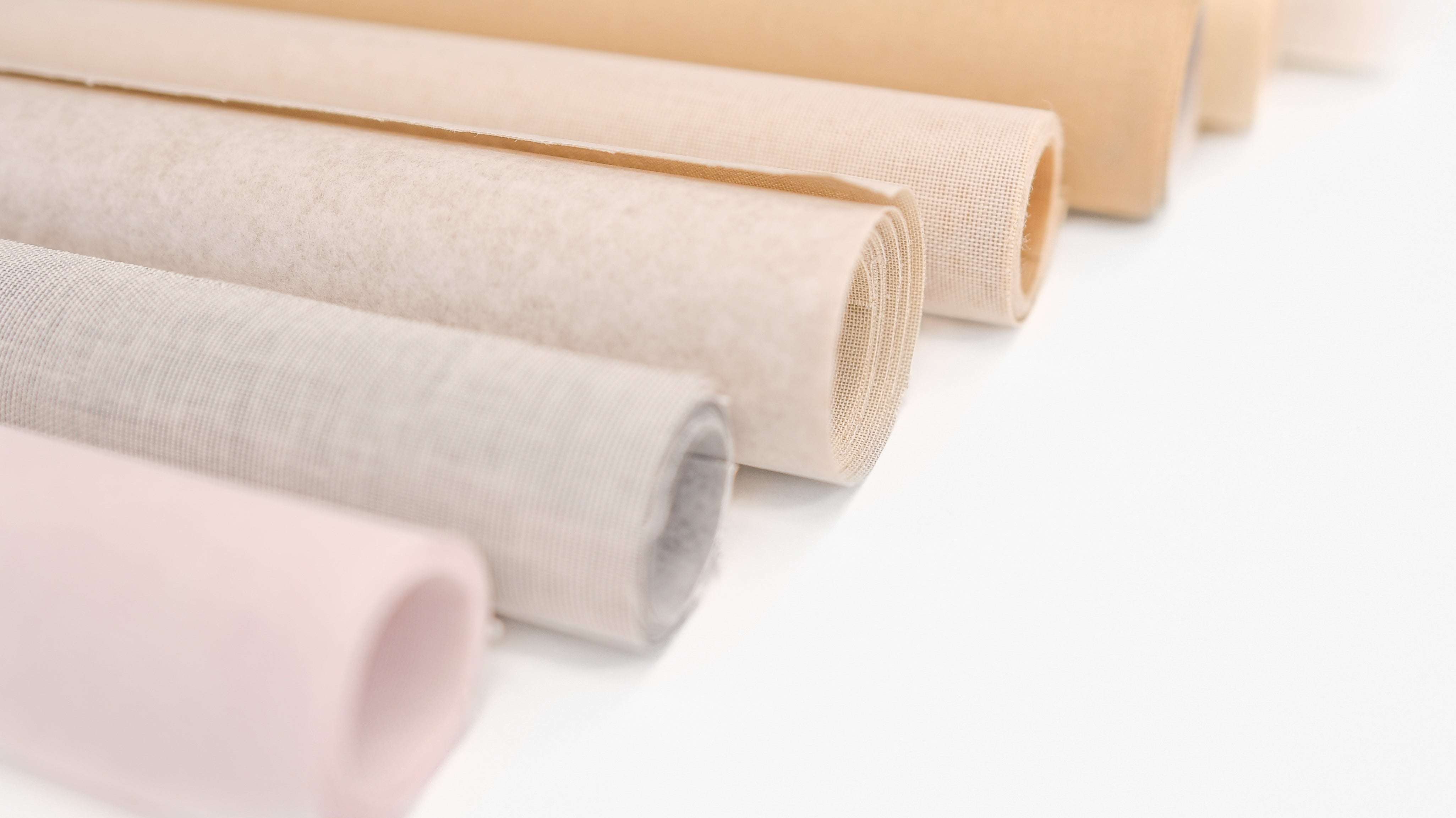 von links nach rechts liegen Buchleinenrollen in gelb, orange, rot, dunkelrot, rosa und violett nebeneinander