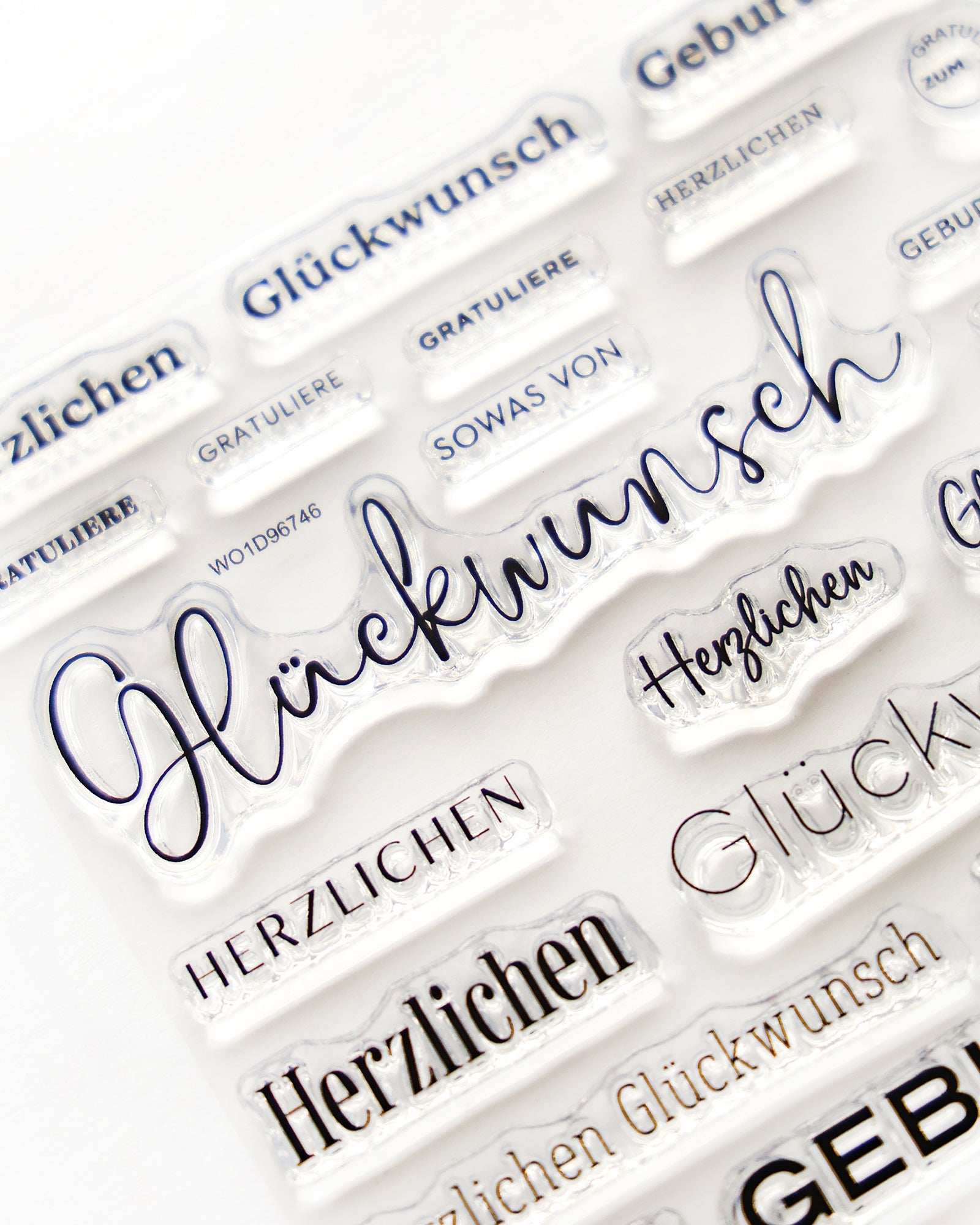 Klare Briefmarken mit deutschen Wörtern wie Glückwunsch, Herzlichen und Gratuliere auf weißem Hintergrund.