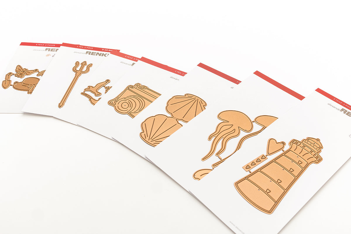 Blätter aus dekorativem Papier mit pastellfarbenen Motiven zum Thema Meer, darunter Fische, Muscheln und Segelboote.