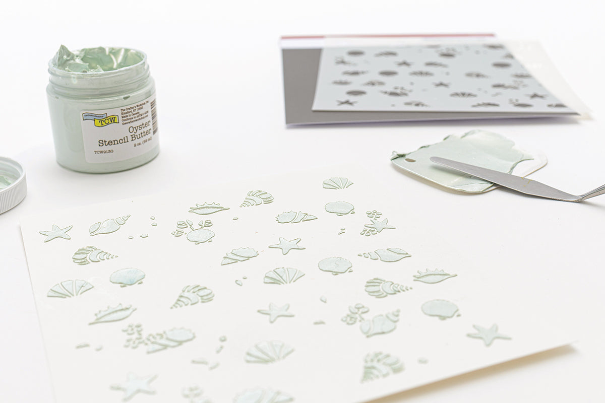 Blätter aus dekorativem Papier mit pastellfarbenen Motiven zum Thema Meer, darunter Fische, Muscheln und Segelboote.
