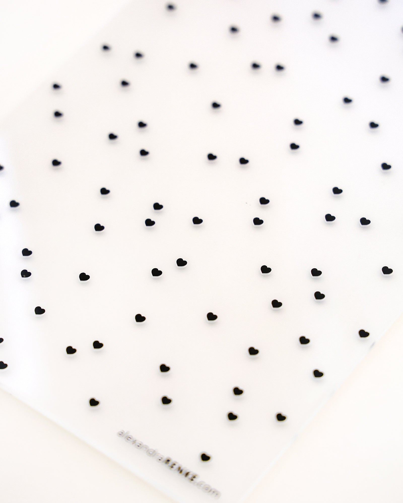 Ein weißes Laken mit einem verstreuten Muster aus kleinen schwarzen Herzformen.