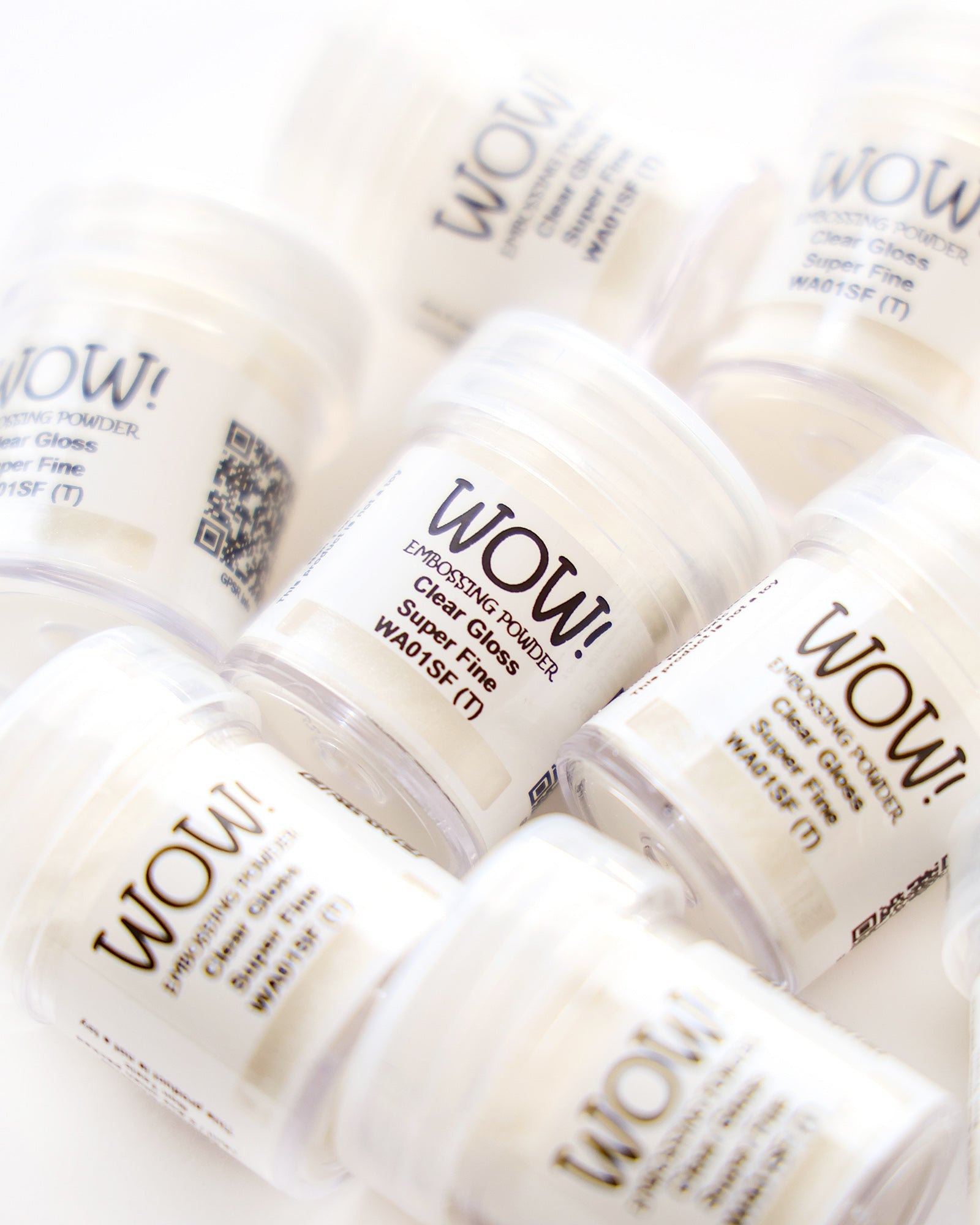 Mehrere Behälter mit WOW! Embossing-Pulver, beschriftet mit Super Fine, auf einer weißen Fläche angeordnet.