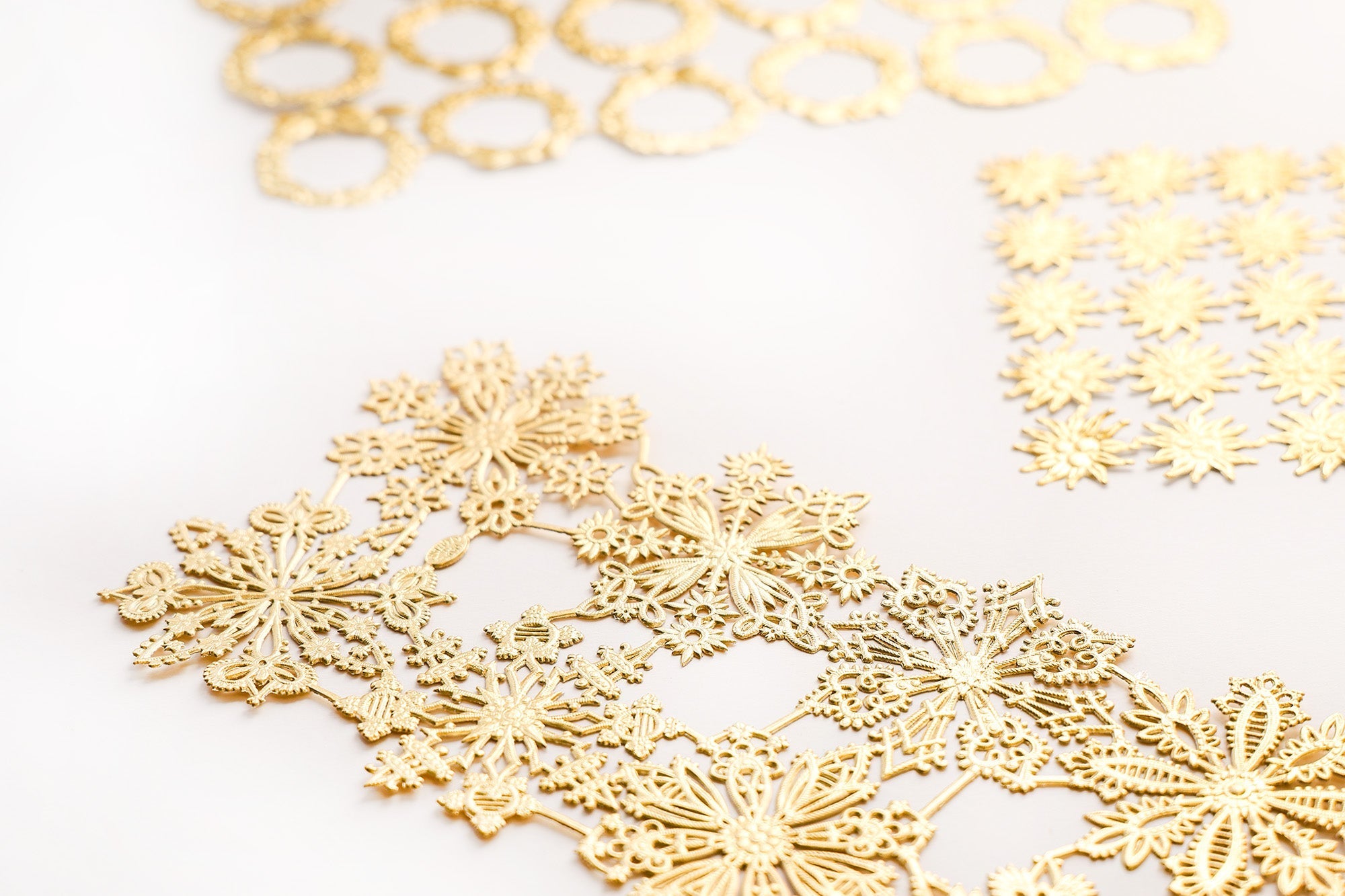 Zarte goldene Papierausschnitte mit komplizierten Mustern auf einer weißen Oberfläche.
