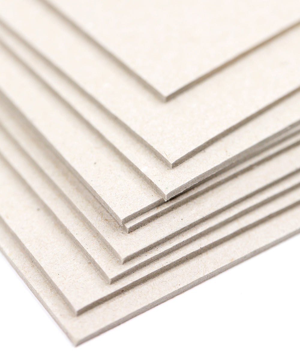 Ein Stapel einfacher, hellbrauner Kartonblätter, die sich auf weißem Hintergrund überlappen.