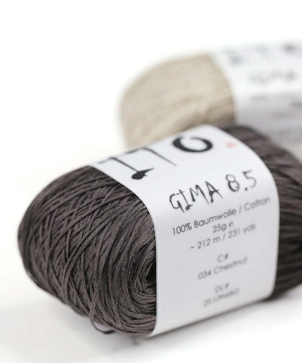 Rosa und weiße Stränge des Baumwollgarns ITO Gima 8.5, die auf einer weißen Fläche gestapelt sind.