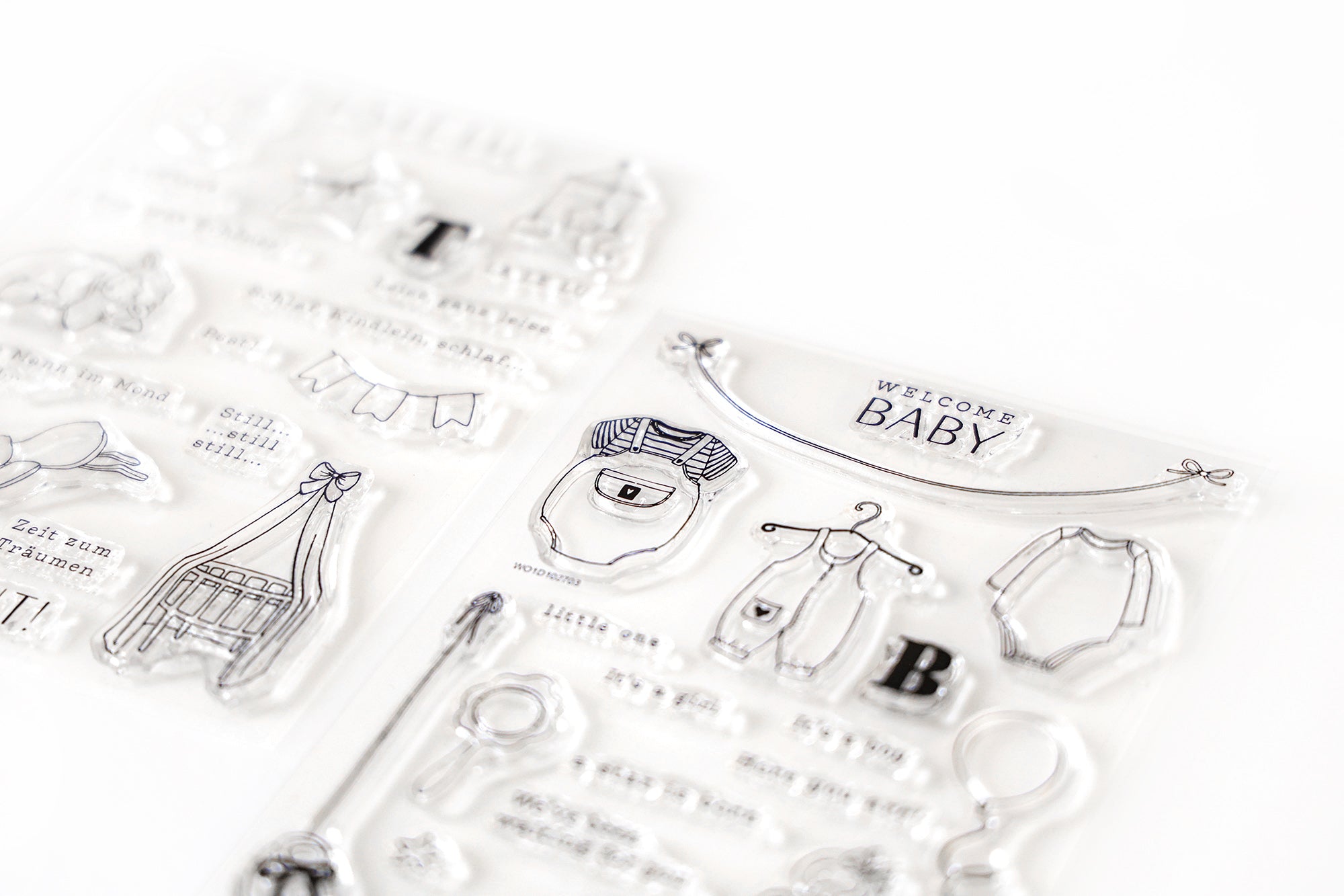 Klarsichtstempel mit Motiven und Text zum Thema Baby, einschließlich Kleidung, Kinderbett, Banner und WELCOME BABY Gruß.