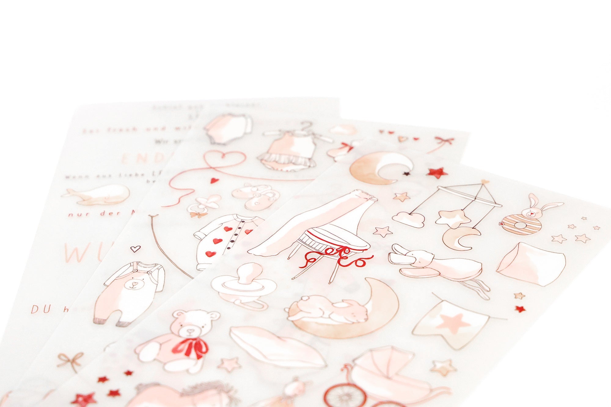 Drei Bögen mit pastellfarbenen Aufklebern, die Babyartikel, Spielzeug, Sterne, Monde und Herzen auf weißem Hintergrund zeigen.