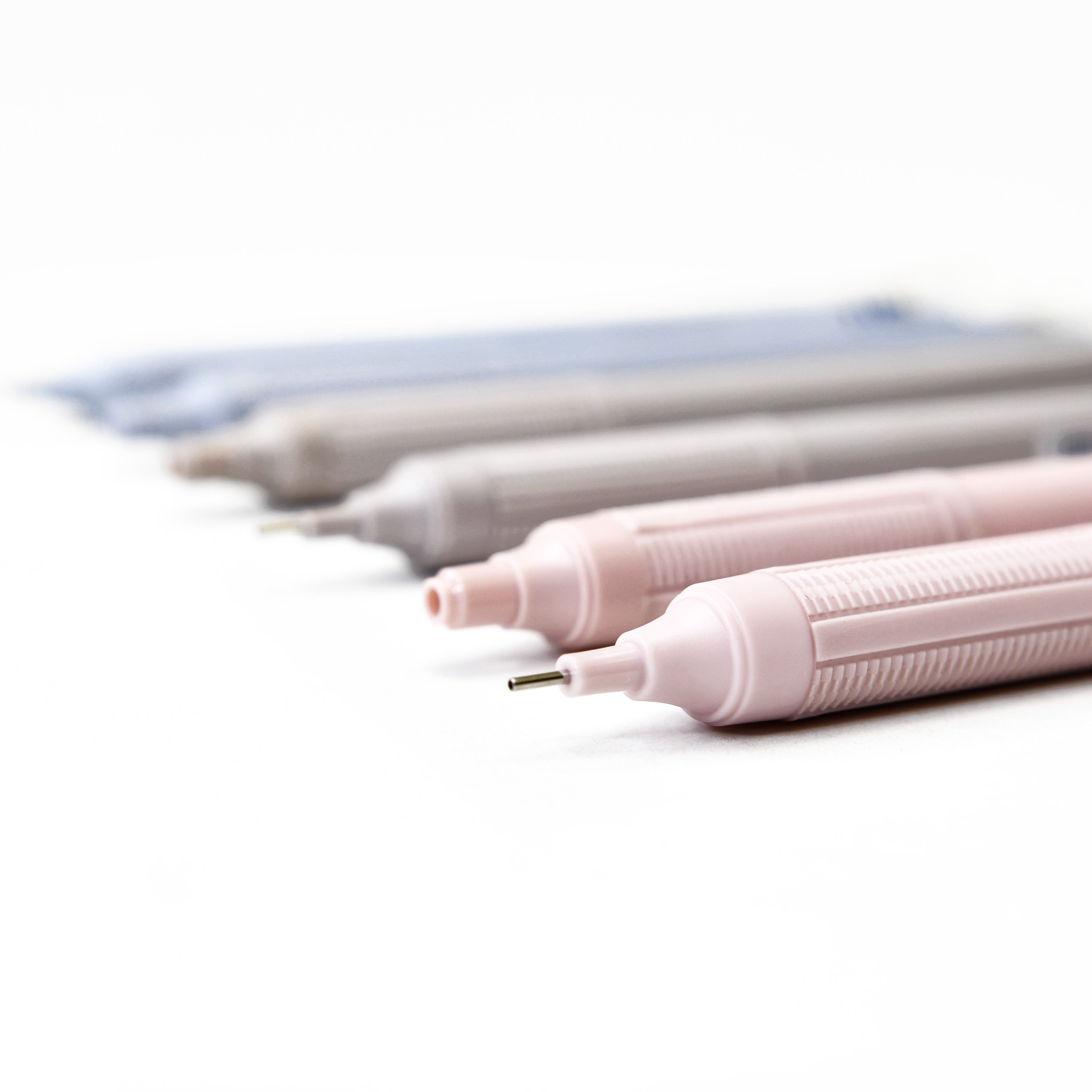 Nahaufnahme der Spitzen von drei Druckbleistiften, die auf einer weißen Fläche aufgereiht sind.