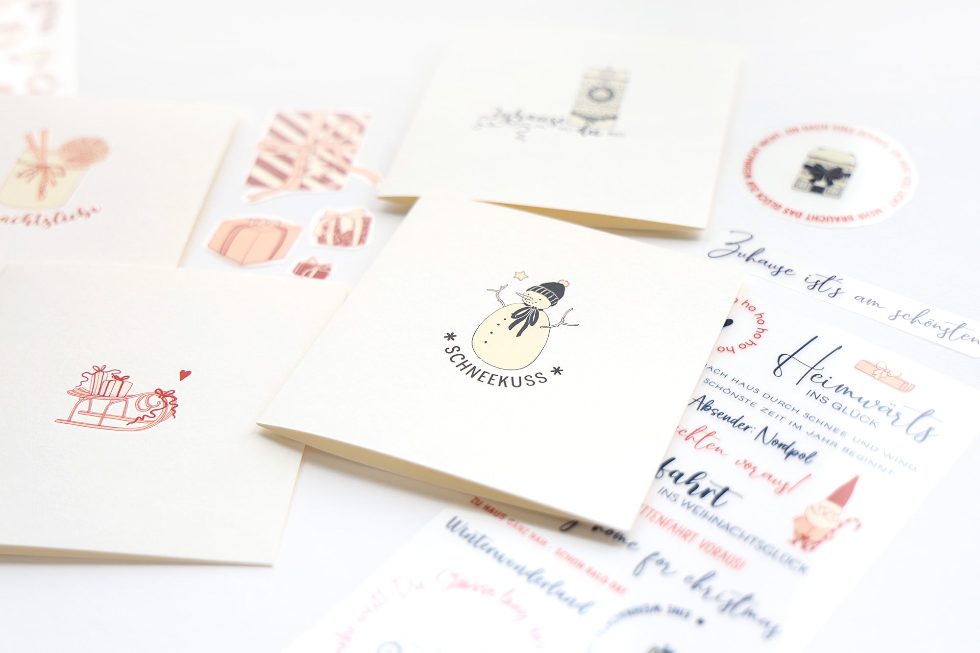 Grußkarten und Aufkleber mit festlichen und skurrilen Motiven auf einer weißen Oberfläche.