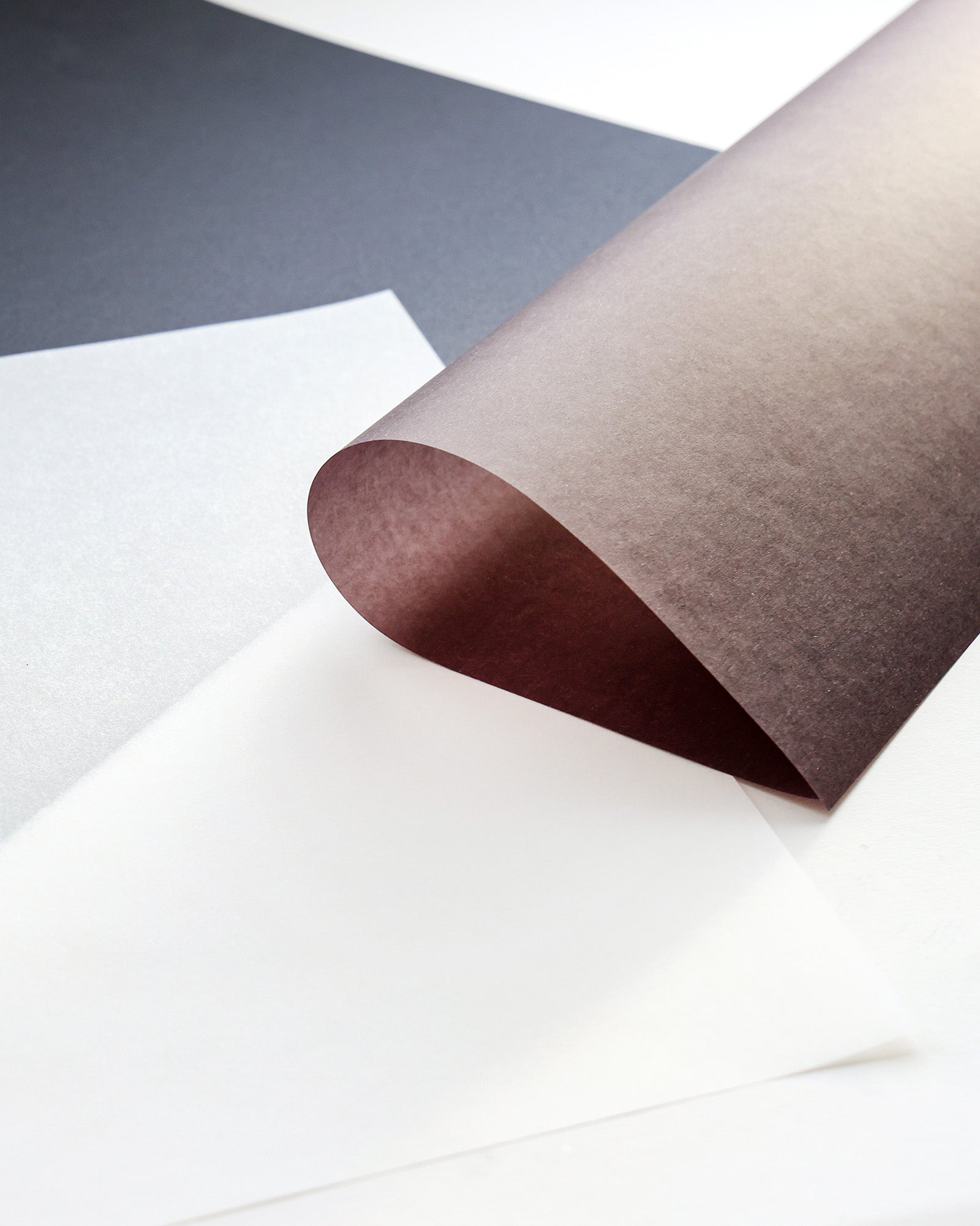 Gebogenes braunes Papier auf weißen und schwarzen Blättern in minimalistischem Stil.