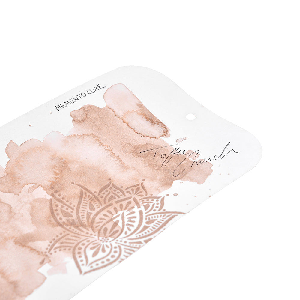 Eine weiße Karte mit braunen Aquarell-Mandalas und den Texten "Toffee Crunch" und "Memento Luxe" von Tsukineko, die mit Pigmenttinte gestempelt wurden, die sich ideal zum Stempeln auf Textilien eignet. Perfekt für Ihr Lieblings-Stempelkissen.