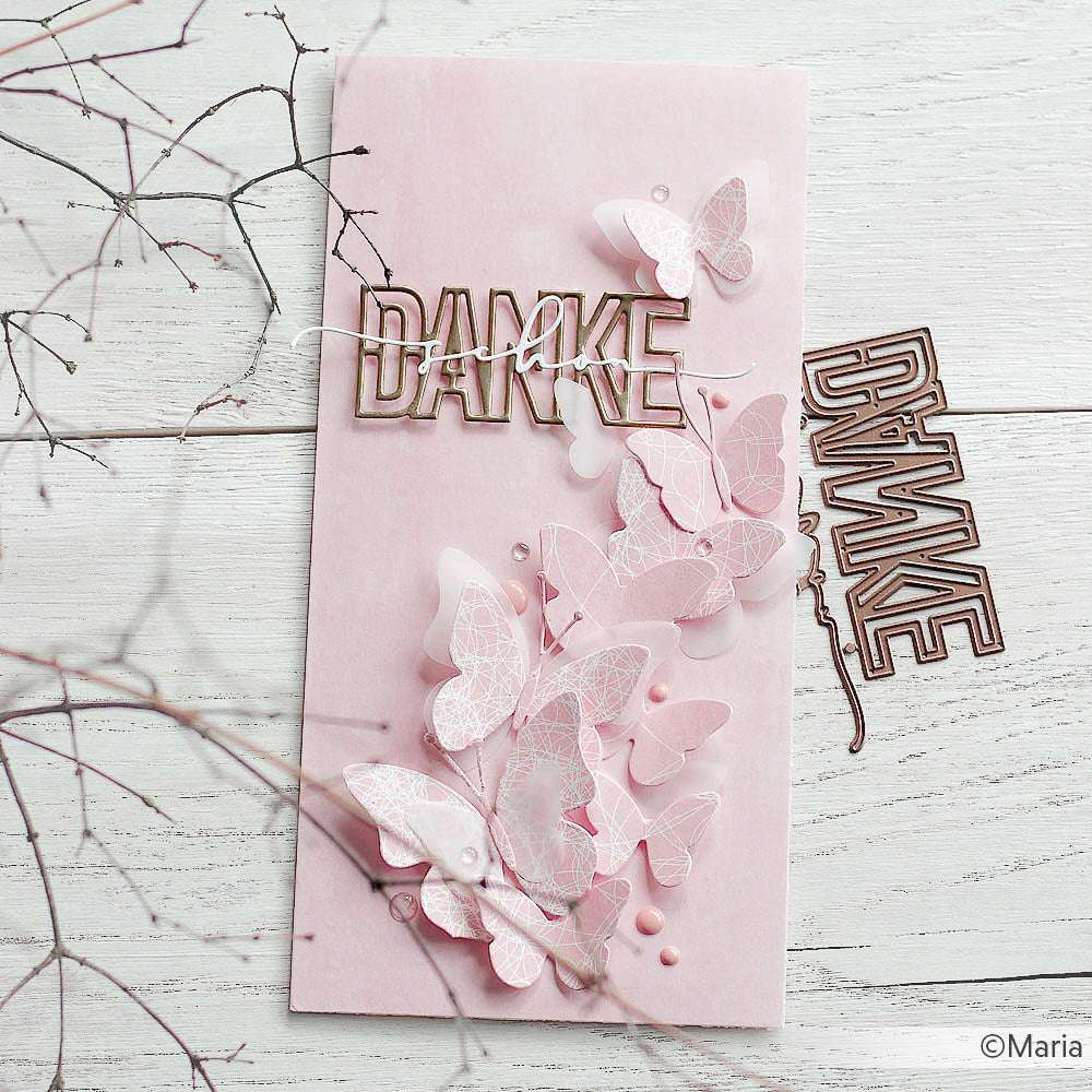 Handgefertigte rosafarbene Karte von Alexandra Renke, gestaltet mit Designpapier und geschichteten Schmetterlingen, mit DANKE in Gold von einer Motivstanze Danke schön, ausgestellt auf einer weißen Holzfläche.