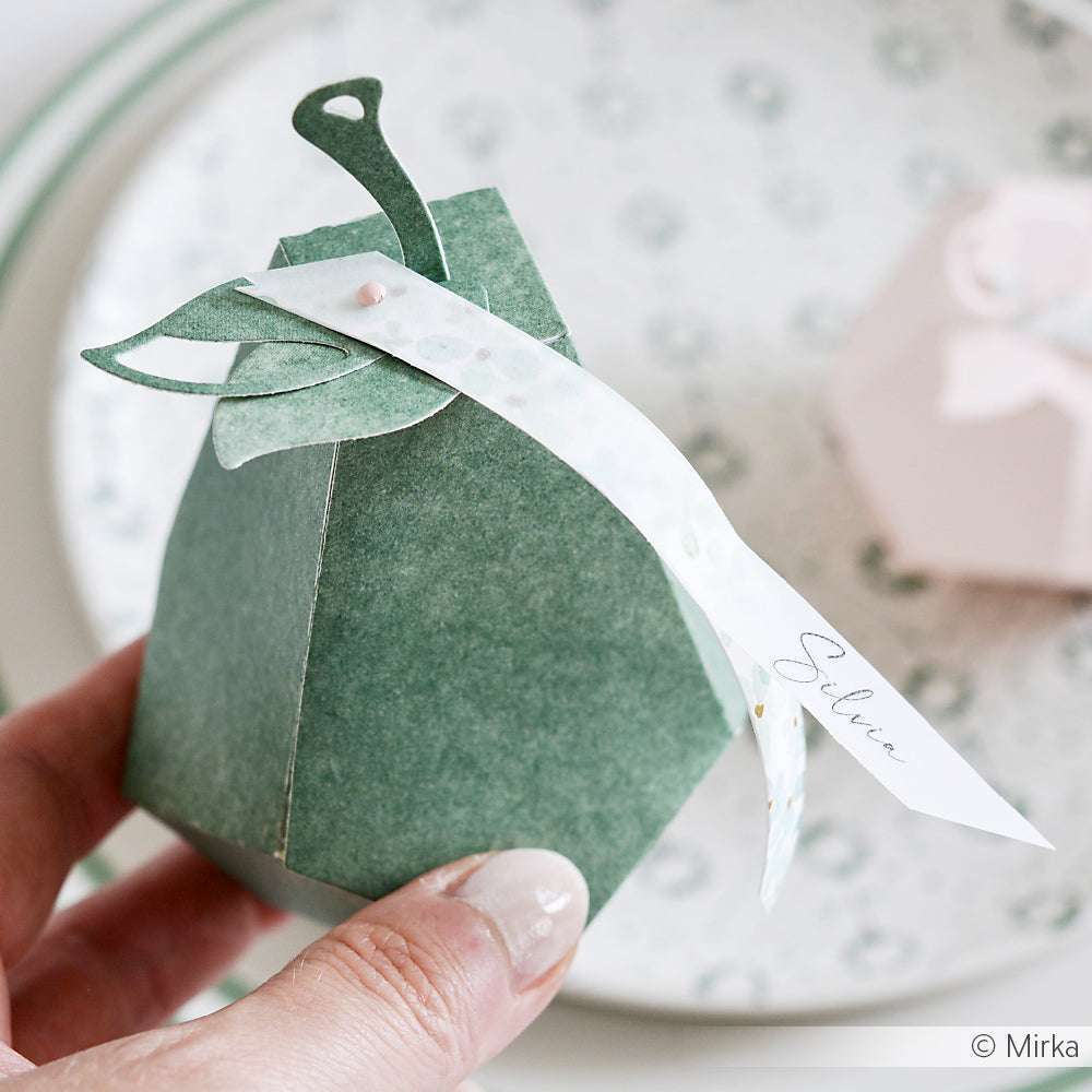 Eine Hand hält eine grüne, birnenförmige Geschenkschachtel aus Alexandra Renke Zypressengrün Designpapier, die mit einem weißen Namensschild mit der Aufschrift Silvia versehen ist.