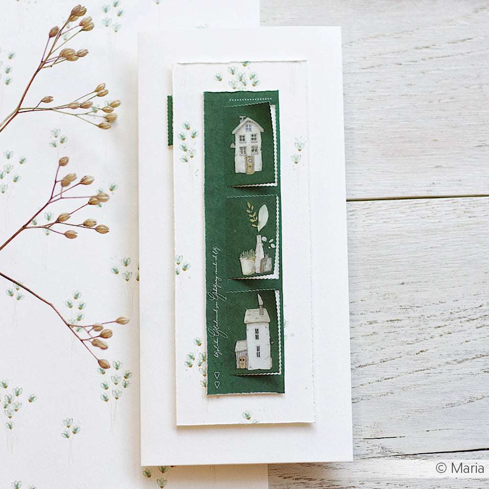 Handgefertigte Karte mit drei grünen Paneelen von Alexandra Renke Designpapier mit weißen Hausillustrationen, die auf einer weißen Holzoberfläche abgebildet sind. Ideal zum Basteln und für kreative Papierprojekte.