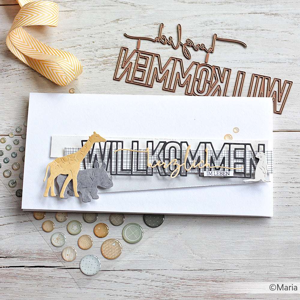 Weiße Karte mit "WILLKOMMEN"-Schriftzug, Giraffen- und Nashornausschnitten und Knöpfen auf Holz - hergestellt aus Alexandra Renke Designpapier 200g/m², ideal für einzigartige Papierprojekte.