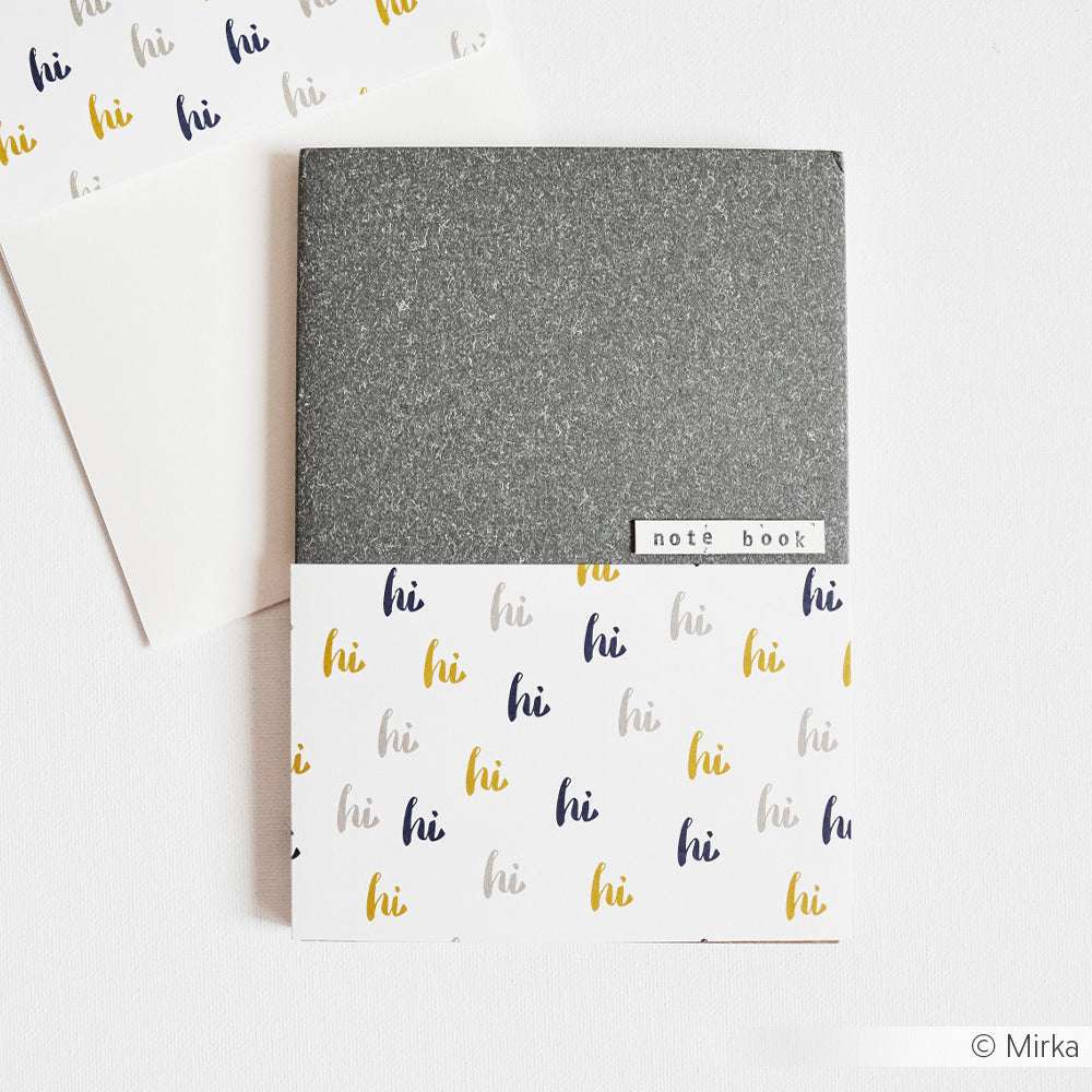 Ein Notizbuch von Alexandra Renke mit einem grauen Oberteil und einem mehrfarbigen "Hallo" auf dem weißen Unterteil - ideal für Papierprojekte oder um Grußkarten-Designs einen verspielten Touch zu verleihen.