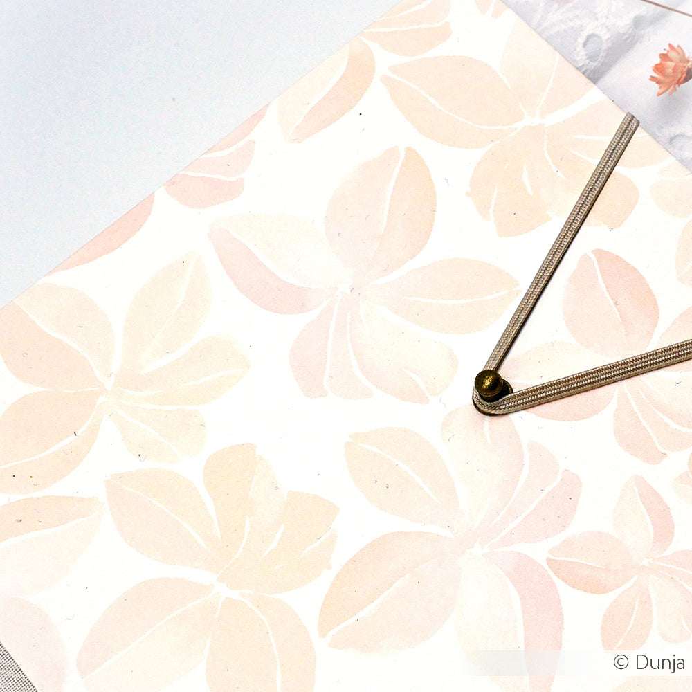 Das beige- und blassrosa Designpapier Blüten Muster von Alexandra Renke zeigt elegante florale Muster, die sich perfekt für Papierprojekte eignen, mit Metallutensilien in der oberen rechten Ecke.