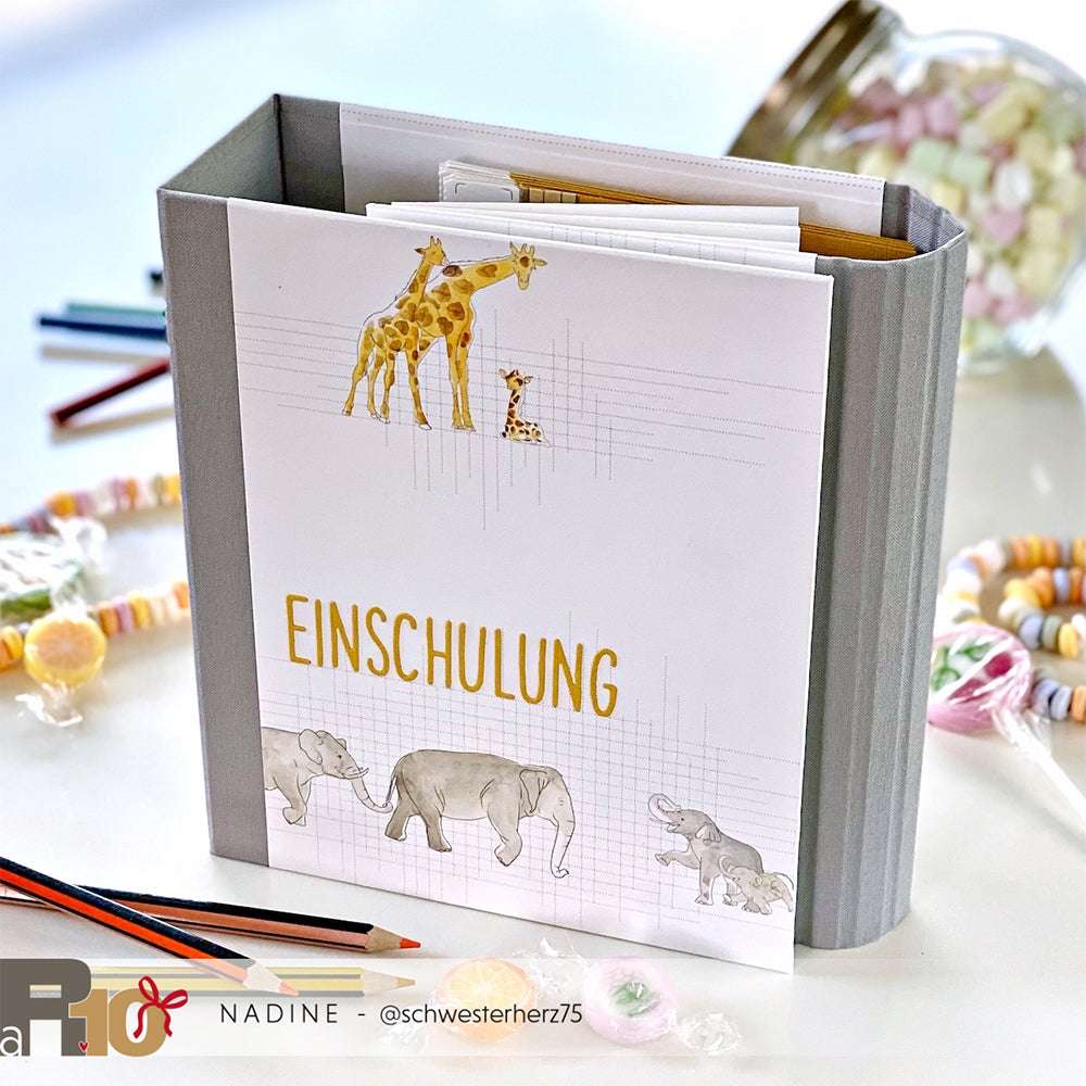 Graue Mappe von Alexandra Renke mit Giraffen- und Elefantenillustrationen, inspiriert von der afrikanischen Tierwelt, beschriftet mit EINSCHULUNG und akzentuiert mit bunten Bonbons - eine lebendige Option für Papierprojekte oder einzigartiges Designpapier.