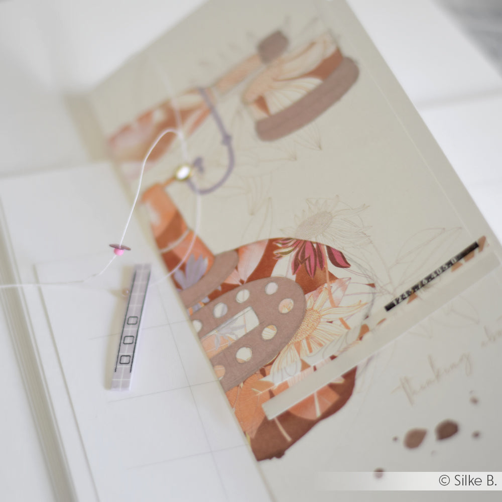 Grußkarte von Alexandra Renke mit einem abstrakten Motiv, Nadel und Faden sowie einem Teststreifen auf Weiß - ideal für die Buchbinderei oder kreative Papierprojekte mit Ihrem Lieblingsdesignpapier.