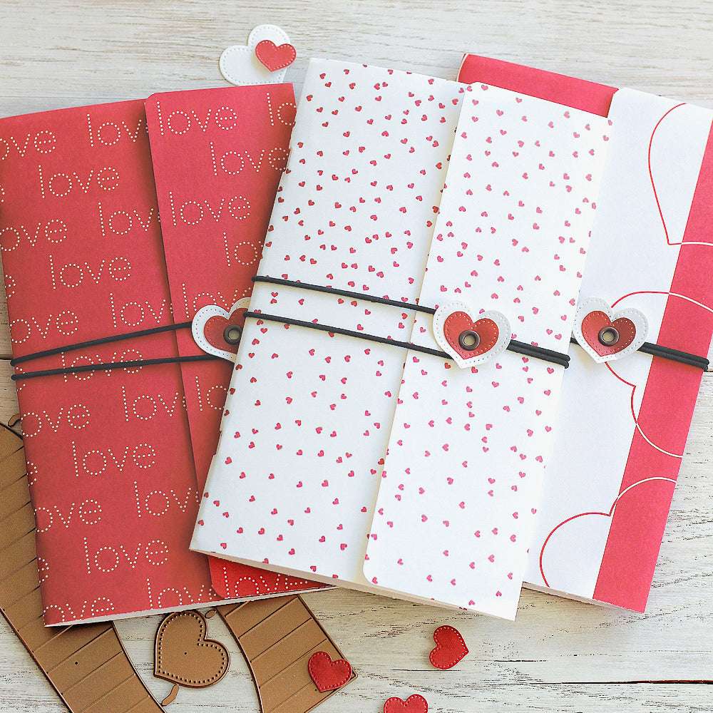 Drei Valentinskarten mit Herzmotiven und passenden Herzbändern aus rotem Premium-Designpapier von Alexandra Renke auf einer hellen Holzunterlage.