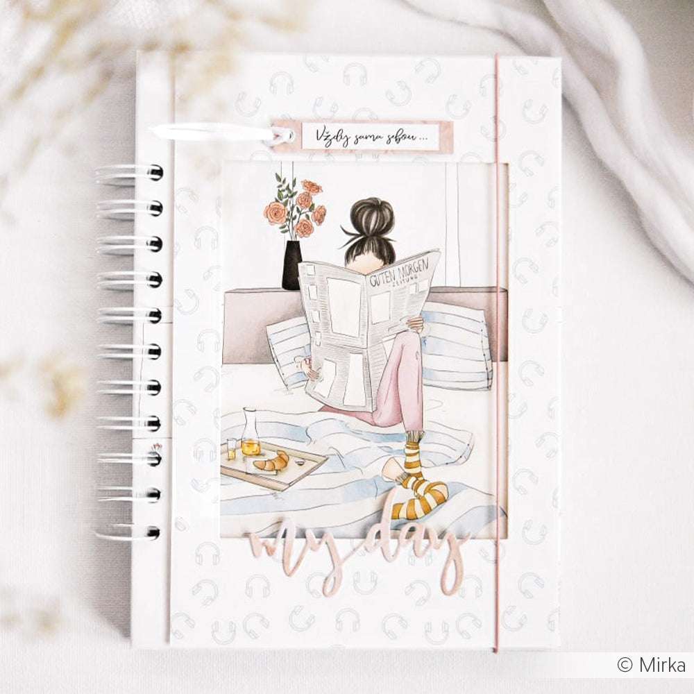 Das Notizbuch-Cover von Alexandra Renke zeigt eine lesende Frau im Bett mit Frühstück auf einem Tablett - eine ideale Inspiration für Papierprojekte oder passende Grußkarten.