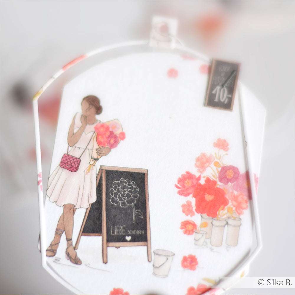 Illustration einer Frau in einem weißen Kleid, die Blumen neben einer Kreidetafel und einer lebhaften rosa Blumenauslage hält, die den Flower-Power-Stil von Alexandra Renke zeigt.