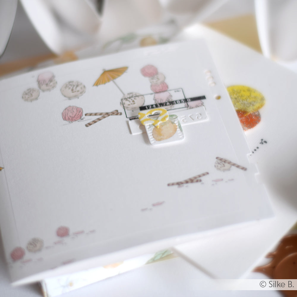 Eine Nahaufnahme einer weißen Alexandra Renke Grußkarte mit pastelligen Eis-Illustrationen und einzigartigen Verzierungen - ideal für Papierprojekte oder kreatives Basteln mit speziellem Designpapier.