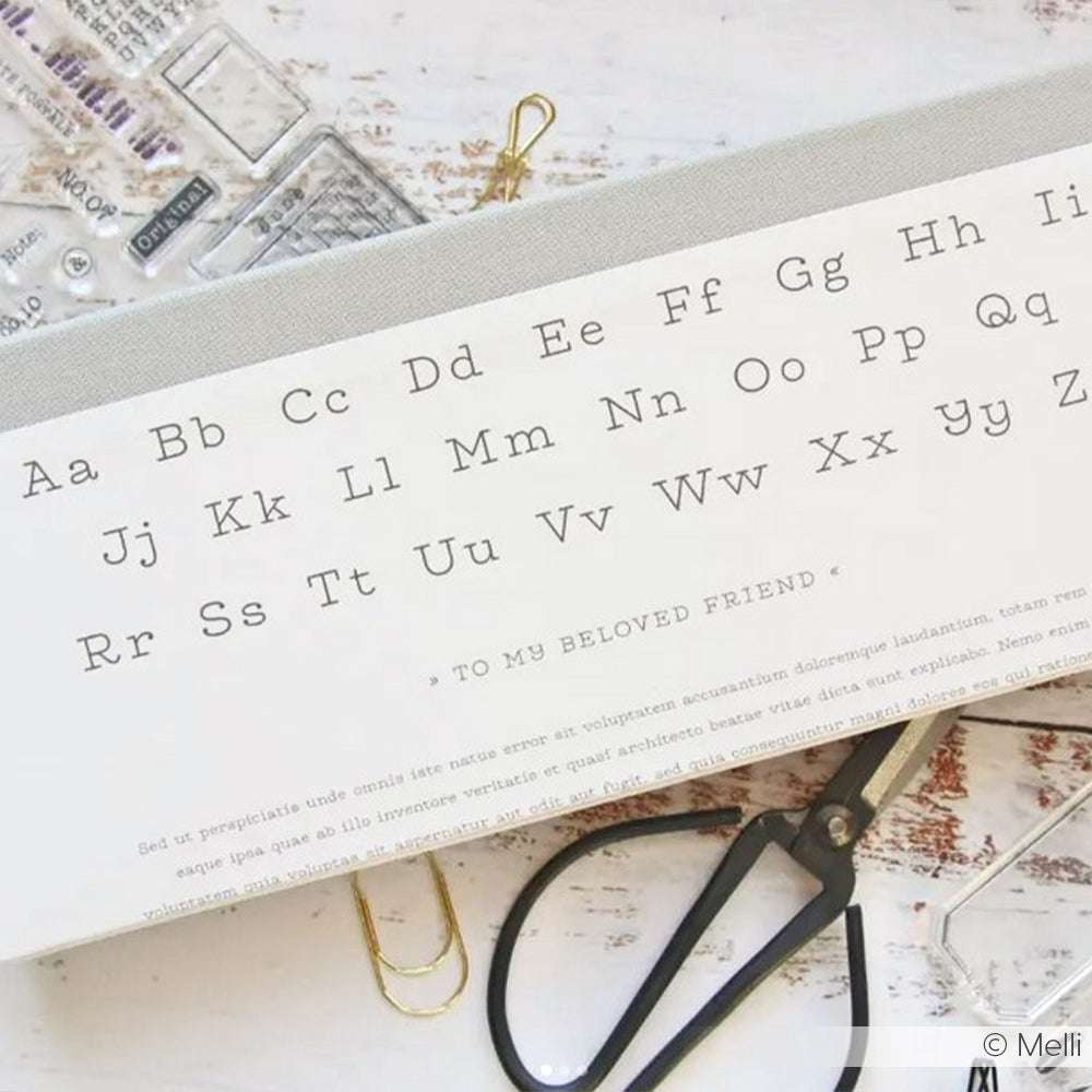 Eine Karte von Alexandra Renke zeigt das Alphabet in Groß- und Kleinbuchstaben, dargestellt mit Schere und Büroklammern - ideal für Papierprojekte oder kreative Buchbinderei.