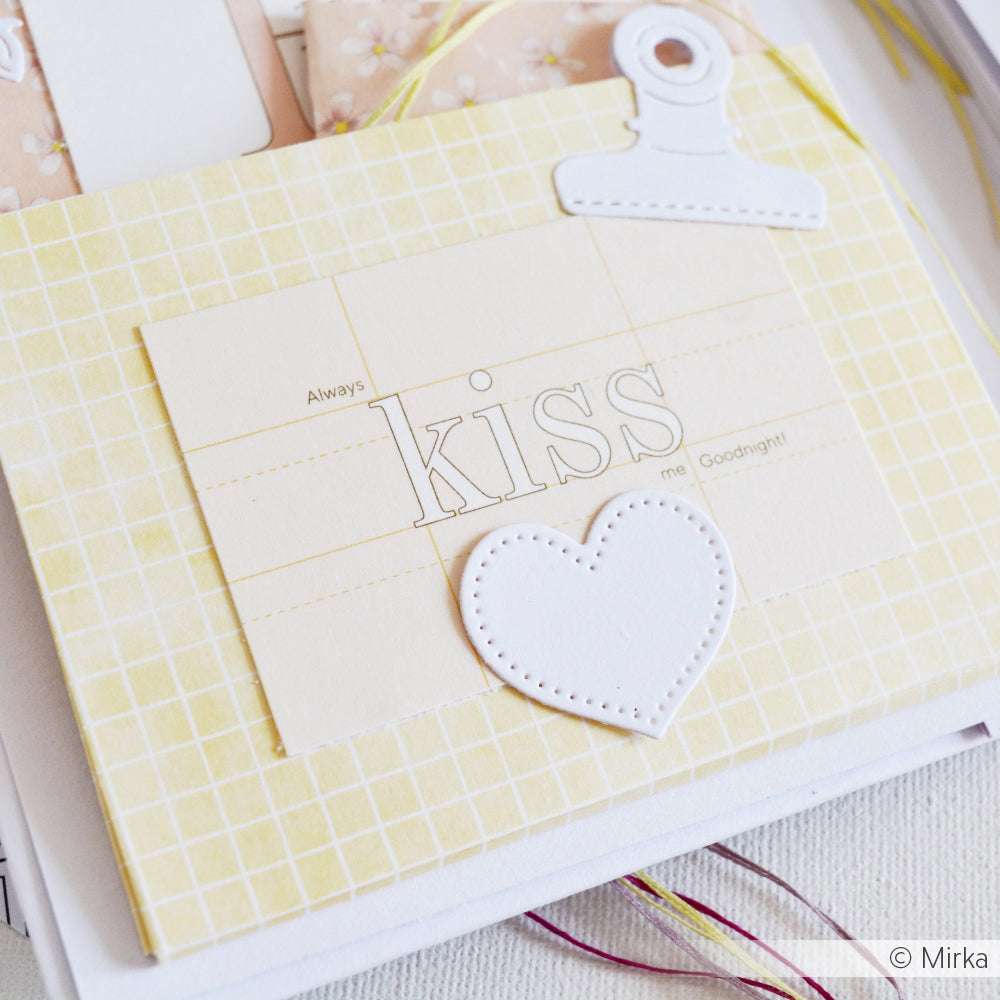 Eine Karte mit "KISS" und "Always", einem gestickten Herz und einer weißen Büroklammer auf gelbem Gitter Designpapier aus der Kollektion Kärtchenbogen Floral Papierprojekte von Alexandra Renke.