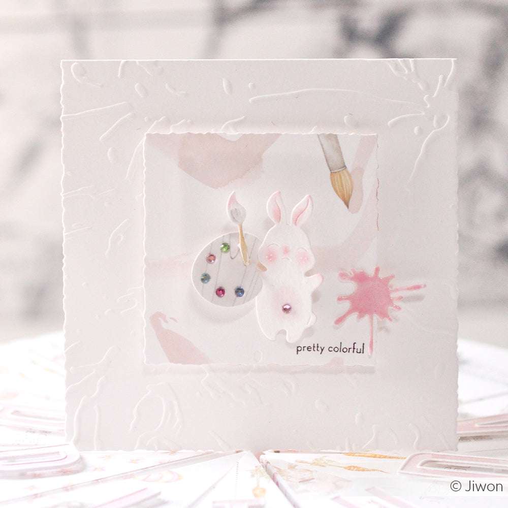 Weiße Grußkarte von Alexandra Renke mit einem Hasen, einer Farbpalette, rosa Spritzern und "ziemlich bunt" - ideal für Papierprojekte oder als kreativer Beitrag zu Ihrer nächsten Designpapier-Kollektion.