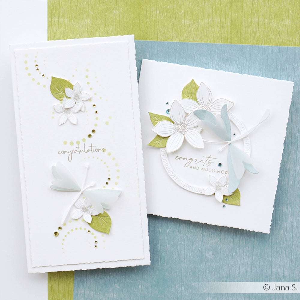 Zwei handgefertigte weiße Karten von Alexandra Renke, verziert mit 3D-Blumen, grünen Blättern, Libellen und einem Glückwunschtext. Gefertigt mit Designpapier Holzstruktur für eine einzigartige Note - perfekt für besondere Anlässe.