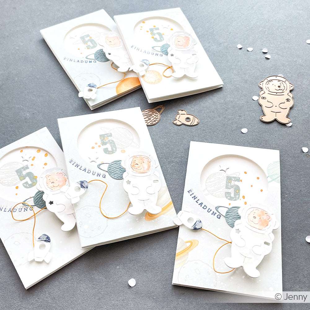 Fünf handgefertigte Geburtstagseinladungen zum Thema Astronaut von Alexandra Renke, mit Designpapier Planeten und Weltraumausschnitten. Perfekt für kreative Papierprojekte, zeigen sie einzigartige Buchbinderei-inspirierte Akzente auf einem hellen Hintergrund.