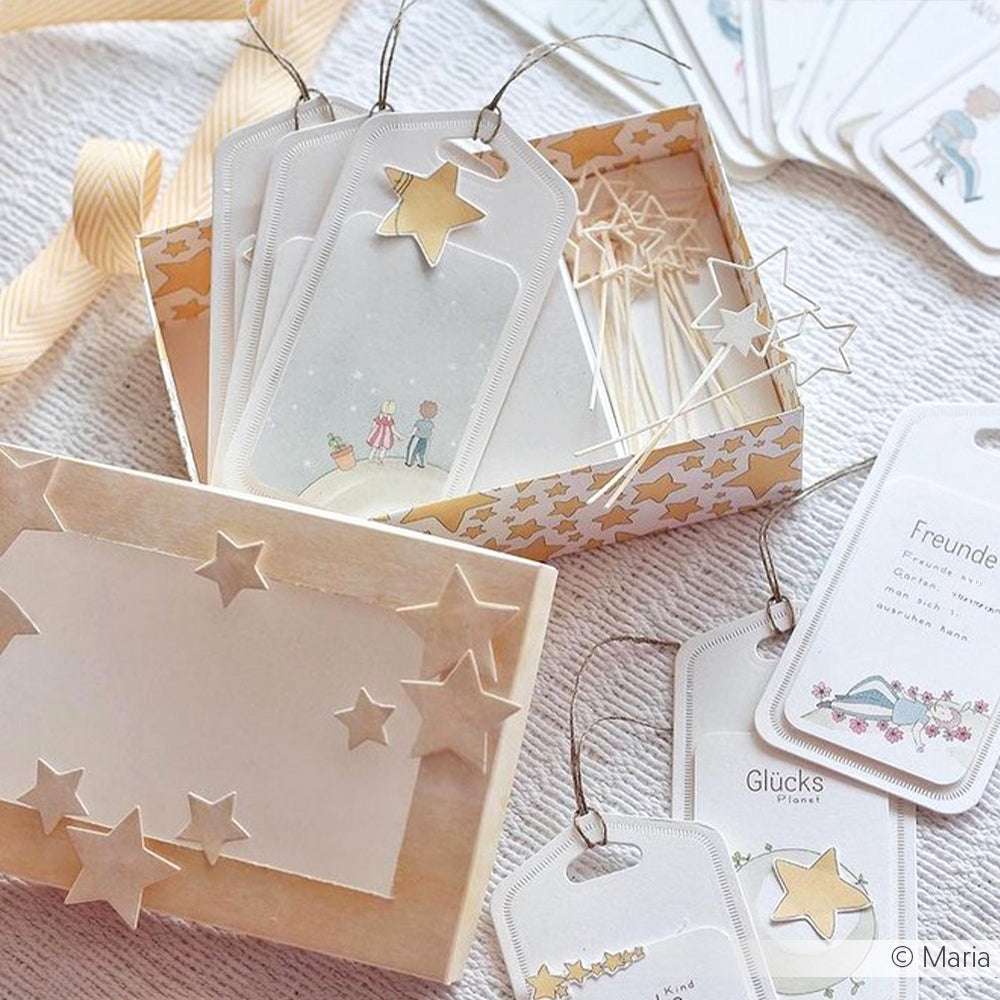 Skurrile Geschenkanhänger von Alexandra Renke mit gelben Sternen und bezaubernden Illustrationen, arrangiert in einer dekorativen Schachtel mit Schleifenband - perfekt für Papierprojekte.
