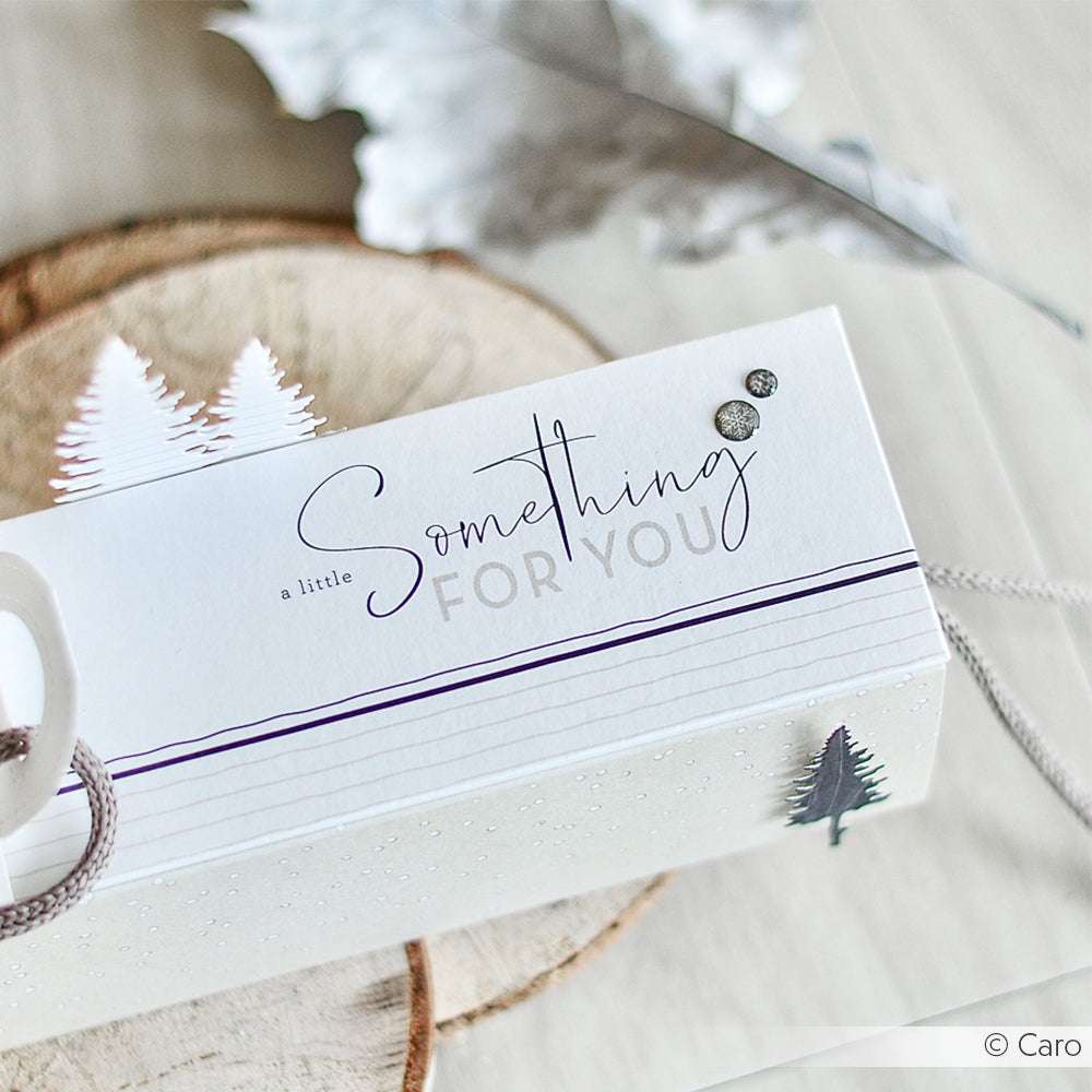 Ein weißer Geschenkkarton mit der Aufschrift "Something for you", verziert mit kleinen Bäumchen aus Alexandra Renke Designpapier, steht auf einer Holzfläche - die perfekte Inspiration für Papierprojekte oder handgemachte Grußkarten.