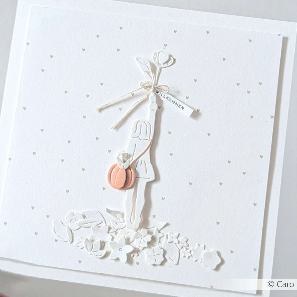 Weiße Karte mit einer Mädchensilhouette mit Blumen, einer pfirsichfarbenen Tasche und einem "Willkommen"-Anhänger - gebastelt mit Alexandra Renke Designpapier Herzchenregen Grau für einzigartige Papierprojekte.