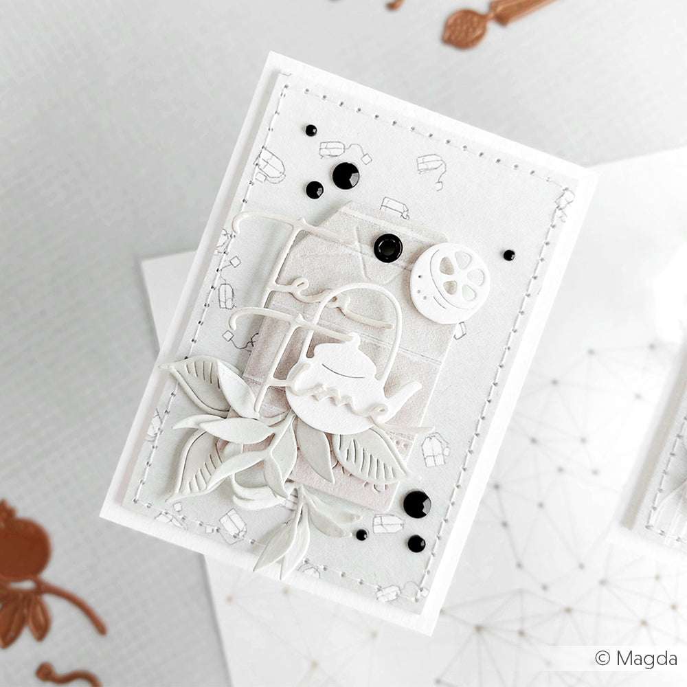 Handgefertigte Grußkarte von Alexandra Renke mit einer weißen Teekanne, Blättern und schwarzen Punkten auf einem gestickten, geschichteten Designpapier-Hintergrund.