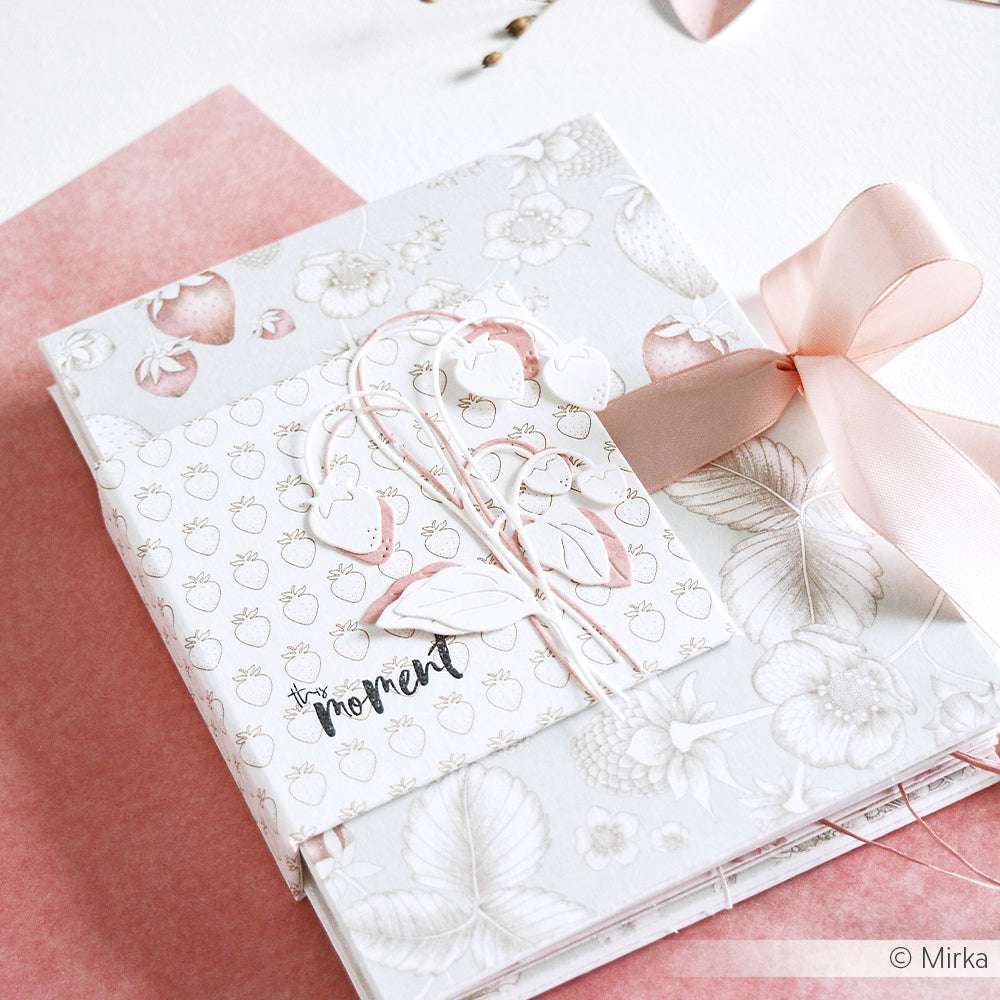 Das pastellrosa-weiße Scrapbook von Alexandra Renke ist mit einem Erdbeermotiv, Satinband zum Binden und Designpapier-Ausschnitten versehen - ideal für charmante Papierprojekte.