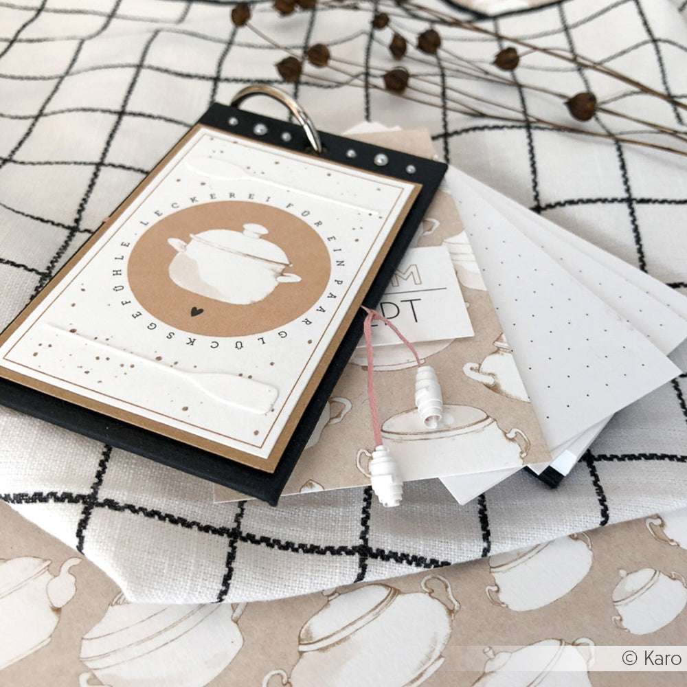 Ein handgefertigtes Rezeptkartenset von Alexandra Renke mit charmanten Küchenmotiven auf hochwertigem Designpapier, das auf einem karierten Tuch präsentiert wird.