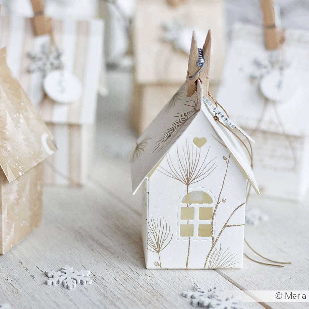 Kleines weißes Papierhaus mit goldenen Motiven, Kiefernzweig-Akzenten, Geschenktüten und Schneeflocken - ideal für festliche Projekte mit Ihrem Lieblingsdesignpapier von Alexandra Renke.